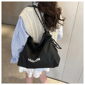 Detail einer großen schwarzen Nylon-Tasche mit FASHION-Buchstaben und gewebten Seilriemen