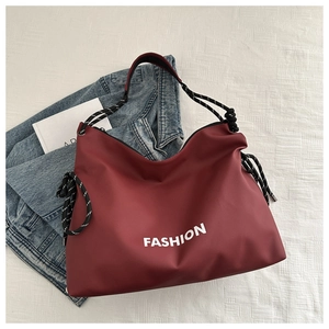 Detail der roten großen Einkaufstasche mit weißem FASHION-Aufdruck und Seilgriffen