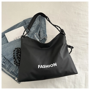Detail der schwarzen Tragetasche mit FASHION-Aufdruck und gewebtem Seilknoten-Riemen