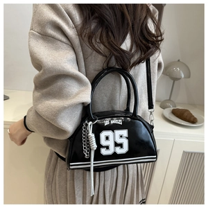 Detail of glossy black Los Angeles 95 bowling bag with silver chain and knot charms