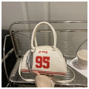 Close-up of cream bowling bag with red Los Angeles print and silver chain accessory