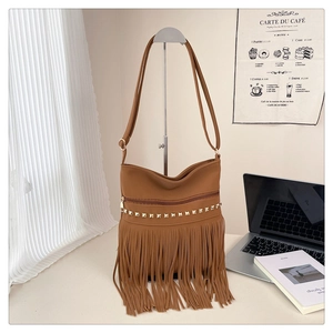 Borsa tote marrone con borchie dorate e lunghe frange appesa in una stanza accogliente