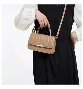 Detailed view of khaki quilted crossbody bag featuring wave stitching and gold hardware