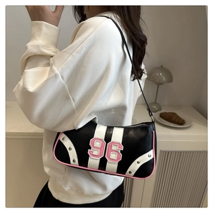 Close-up of black baguette bag featuring pink number 96 patch and silver rivet details