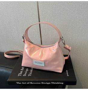 Close-up of pink glossy patent leather handbag with adjustable strap and brand label