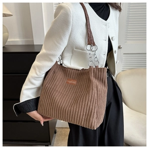 Brown corduroy tote bag shown on model featuring a metallic chain and leather strap