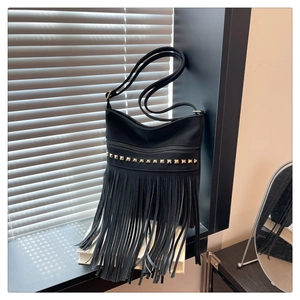 Détail du sac en similicuir noir avec clous dorés et longues franges décoratives élégantes