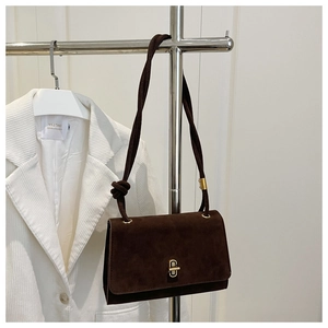 Detail of dark brown suede shoulder bag with golden clasp and braided knot strap