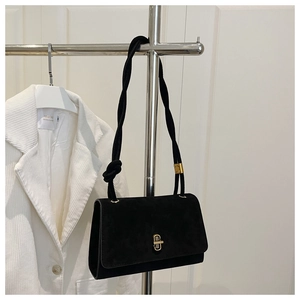 Detail of black suede evening bag with golden twist lock and twisted rope strap