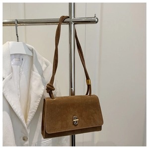 Detailed close-up of brown suede shoulder bag with a gold metal twist-lock and knotted strap