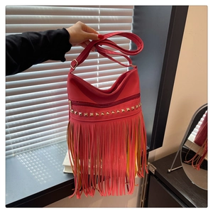 Détail du sac rouge en simili cuir avec rivets dorés, franges longues et bandoulière