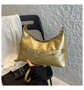 Detail of metallic gold hobo bag featuring belt straps and circular textured metal buckle