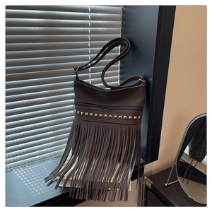 Détail du sac bandoulière en cuir marron foncé avec rivets métalliques et franges