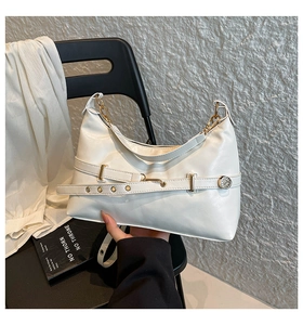 Close-up of white leather handbag featuring golden buckle detail and belt decoration