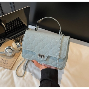 Close-up of light blue quilted crossbody bag with silver twist lock and chain strap