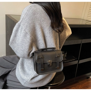 Detail of vintage black leather messenger bag with adjustable strap and metal buckle