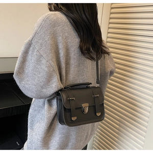 Rear view of model wearing a black minimalist crossbody bag with retro metal buckle