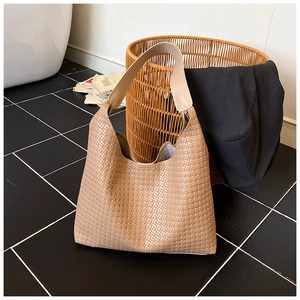 Dettaglio della trama intrecciata beige e della tracolla in pelle della borsa hobo