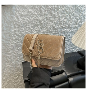 Detail of camel velvet crossbody bag with V-shaped stitching and gold tassel