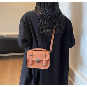 Orange vintage crossbody bag worn by a model in a minimalist interior setting