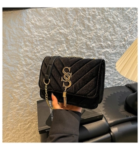 Detail of black velvet quilted handbag with gold hardware and elegant tassel charm