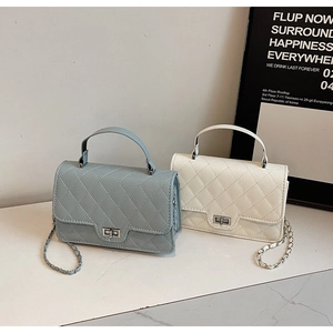 Detail of quilted leather bags in blue and white with metal chain straps and locks
