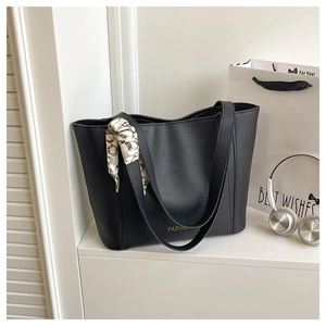Dettaglio della borsa tote in pelle martellata nera con scritte oro e foulard di seta