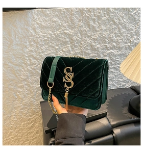 Detail of dark green velvet crossbody bag featuring V-quilting and gold tassel charm