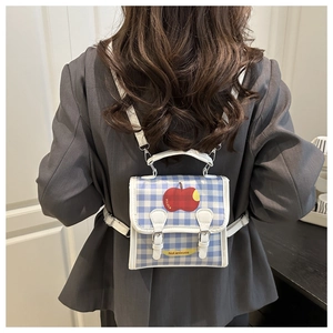Detail of blue and white checkered backpack with red apple print and white straps