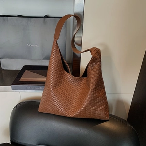 Brown woven hobo tote bag with wide leather strap in a minimalist vintage style
