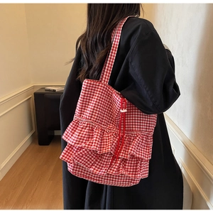 Detail of red and white checkered tote bag with ruffle trim and drawstring closure