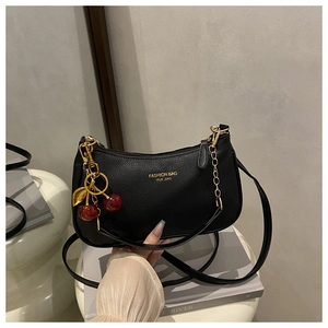 Detail of black lychee texture bag with gold lettering, chain, and cherry pendant