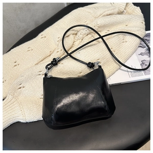 Close-up of black retro shoulder bag showing shiny leather texture and knot detail