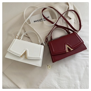 Detail of white and burgundy bags featuring golden V-shaped hardware and fine PU texture