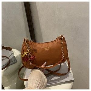 Brown lychee leather crescent shoulder bag with cherry pendant and gold hardware details