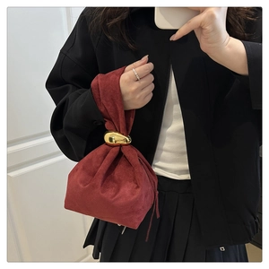Detail of burgundy suede mini handbag with decorative pebble-shaped gold metal hardware