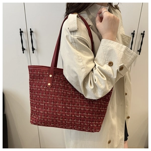 Detail of red plaid tweed tote bag with gold thread weaving and leather strap