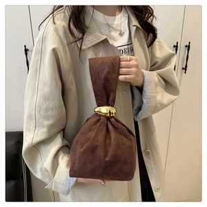 Detail of deep brown suede bucket bag with large golden pebble metal ring handle