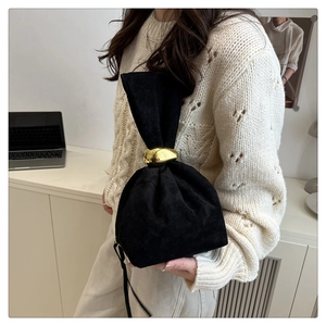 Detail of minimalist black suede bag showing pleated texture and gold metal ring handle