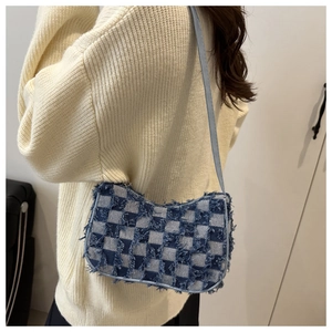 Detail of blue checkerboard denim shoulder bag with vintage frayed edges and strap