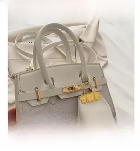 Detail showing white croc-embossed contrast stitching and gold hardware on handbag