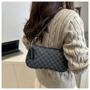 Detail of dark grey baguette bag featuring repeated letter M pattern and silver hardware