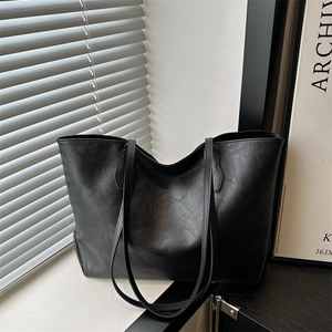 Minimalist black faux leather tote bag with a natural wrinkled texture and double straps