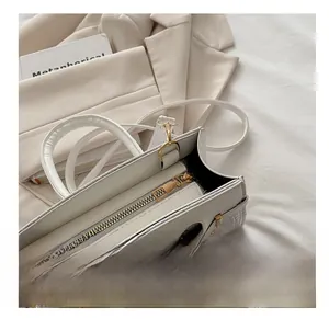 Detail view of white crocodile pattern handbag with gold zipper and metal lock closure