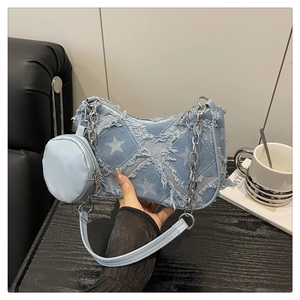 Détail du sac sous l'aisselle en denim bleu avec patchs d'étoiles blanches et chaîne