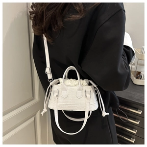 Dettaglio mini borsa bianca con texture a pietra e sacca interna con coulisse su abito nero