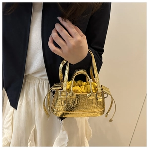 Détail d'un mini sac doré à motif crocodile avec un sac intérieur jaune à cordon