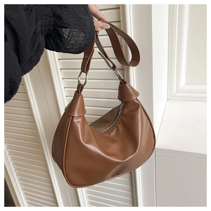Detail of caramel brown leather hobo bag featuring silver metal rings and knot detail