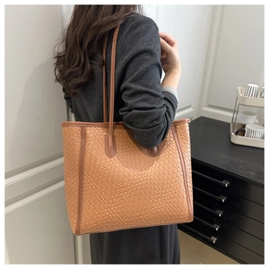 Détail d'un sac cabas en cuir tressé marron clair montrant l'artisanat et la texture