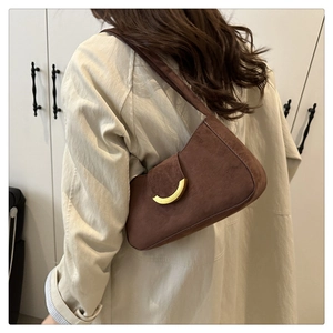Detail view of brown suede shoulder bag featuring a half-moon golden metal buckle